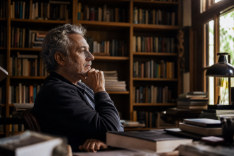 Retrato editorial ilustrativo de um escritor em uma biblioteca, cercado por livros e luz suave