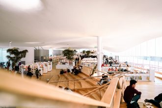 Pessoas leem e relaxam no interior amplo e iluminado de uma biblioteca.