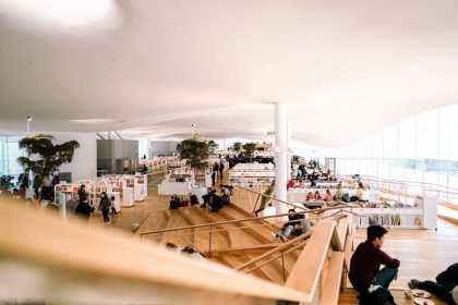 Pessoas leem e relaxam no interior amplo e iluminado de uma biblioteca.
