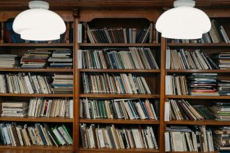 Estantes de madeira organizadas com livros diversos em uma biblioteca iluminada por luz quente