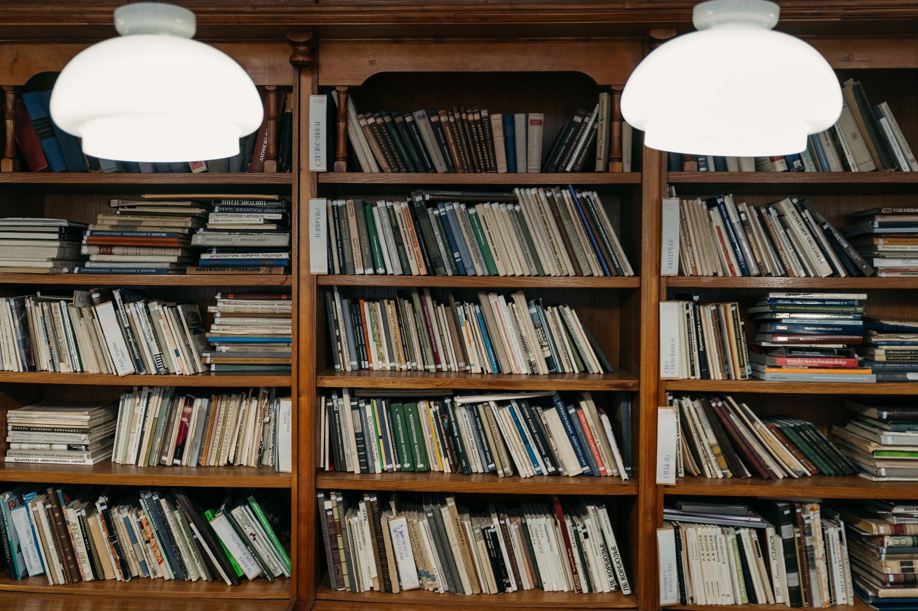 Estantes de madeira organizadas com livros diversos em uma biblioteca iluminada por luz quente